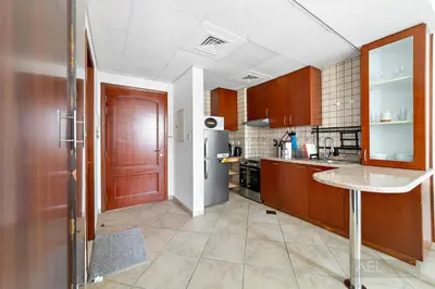 a kitchen with wooden cabinets and a refrigerator at WelHome - Stylish Studio with Park Views in Regent House 2 in Dubai