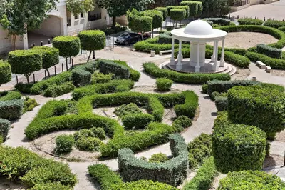 a hedge garden with a white structure in the middle at WelHome - Stylish Studio with Park Views in Regent House 2 in Dubai