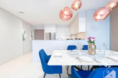 a dining room with a white table and blue chairs at Luxury Burj Royale 4Bed Balcony Burj Khalifa View in Dubai