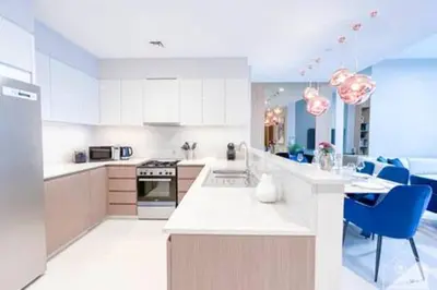 a kitchen with white cabinets and blue chairs at Luxury Burj Royale 4Bed Balcony Burj Khalifa View in Dubai