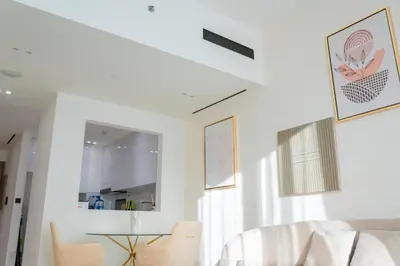 a white living room with a table and chairs at Luxe 1BR 15mins-Beach Best Infinity Pool -Jumeirah Village Circle, JVC ,Dubai in Dubai