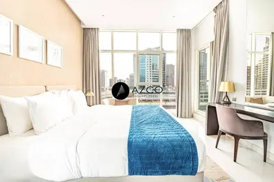 a bedroom with a large bed and a desk with a window at Panoramic 2BR - 3 Balconies & Canal Views - Damac Maison Prive by AZCO Holiday Homes in Dubai