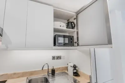 a kitchen with white cabinets and a sink at Luxueux Studio, Top emplacement in Dubai