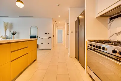 a kitchen with yellow cabinets and a stove at Stylish sea view from new 2BD La Vie in Dubai