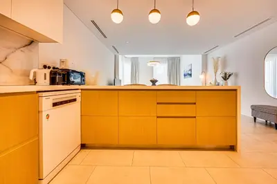 a kitchen with yellow cabinets and a counter at Stylish sea view from new 2BD La Vie in Dubai