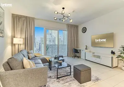 a living room with a couch and a tv at bnbme - Luxury 1BR La Vie Apt Beach Access Pool Gym Balcony & Stunning Dubai Eye Views in Dubai