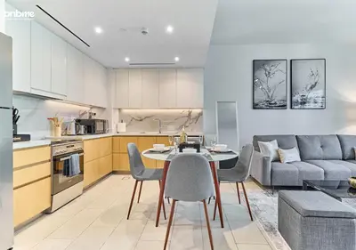 a kitchen and living room with a table and chairs at bnbme - Luxury 1BR La Vie Apt Beach Access Pool Gym Balcony & Stunning Dubai Eye Views in Dubai
