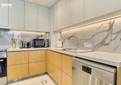 a kitchen with white cabinets and marble counter tops at bnbme - Luxury 1BR La Vie Apt Beach Access Pool Gym Balcony & Stunning Dubai Eye Views in Dubai