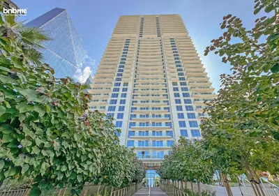 a tall building with trees in front of it at bnbme - Luxury 1BR La Vie Apt Beach Access Pool Gym Balcony & Stunning Dubai Eye Views in Dubai