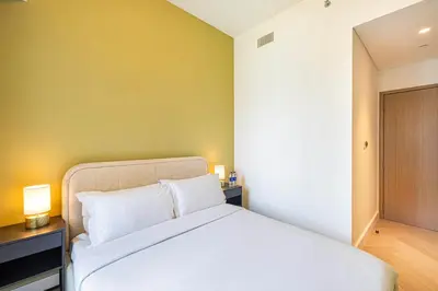 a bedroom with a white bed and a yellow wall at Daniels Luxe 3BR Downtown with Skyline View in Dubai