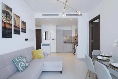 a white living room with a couch and a table at Stylish 2 bedroom apartment in Sobha Hartland in Dubai
