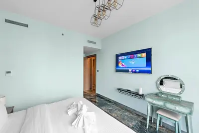 a bedroom with a bed and a desk and a tv at FIRST CLASS 2BR Stunning Fountain View in Dubai