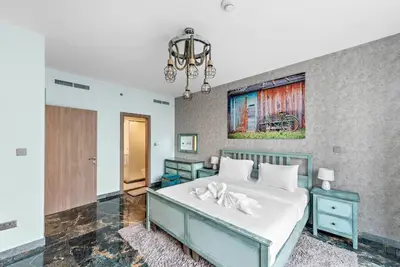 a bedroom with a large white bed and a chandelier at FIRST CLASS 2BR Stunning Fountain View in Dubai