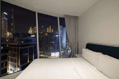 a white bed in a room with a window at Panoramic LUX Apartment with Burj Khalifa View in Dubai