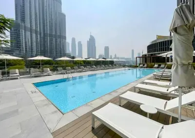 a swimming pool with chairs and umbrellas on a building at Luxury 1BR The Address Opera, Downtown Dubai in Dubai