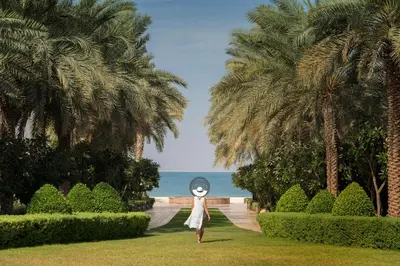 a woman is standing in a park with palm trees at Four Seasons Resort Dubai at Jumeirah Beach in Dubai