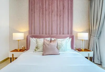 a bedroom with a bed with a pink headboard and pillows at EasyGo - Upgraded 2BDR in BLVD Point with Burj Khalifa View in Dubai