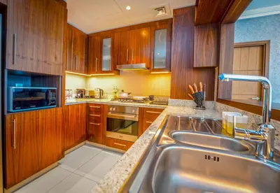 a kitchen with wooden cabinets and a stainless steel sink at EasyGo - Upgraded 2BDR in BLVD Point with Burj Khalifa View in Dubai