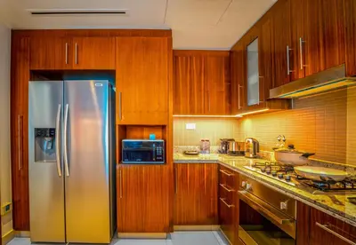a kitchen with wooden cabinets and a stainless steel refrigerator at EasyGo - Upgraded 2BDR in BLVD Point with Burj Khalifa View in Dubai