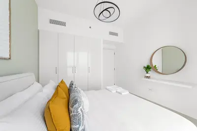 a white room with a bed with yellow pillows at Silkhaus Ultra Luxury 1BDR in New Tower of Downtown in Dubai