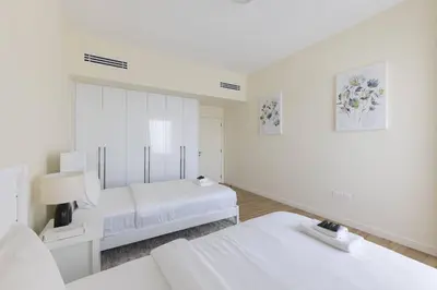 a white bedroom with two beds and a mirror at Luxury Living on the Top Floor Full Marina View in Dubai