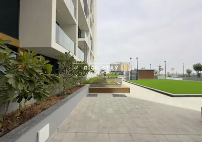 a courtyard of a building with a bench and grass at Exceptional 1 BR in Prive Residences Dubai Hills in Dubai