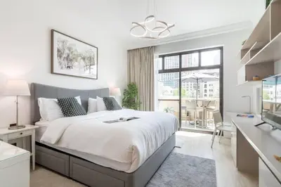 a white bedroom with a large bed and a kitchen at FIRST CLASS 1BR Tranquil Oasis in Old Town in Dubai