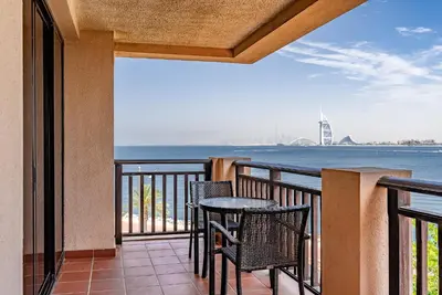 a balcony with a table and chairs and the ocean at Anantara South Residences I Stunning 1 Bedroom Apartment in Dubai