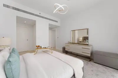 a white bedroom with a bed and a mirror at Maison Privee - Seaside JBR Living w/ Open Sea & Bluewaters Views in Dubai