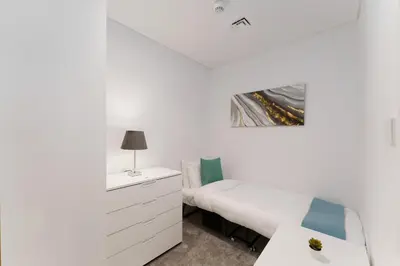 a white bedroom with a bed and a dresser at Maison Privee - Seaside JBR Living w/ Open Sea & Bluewaters Views in Dubai