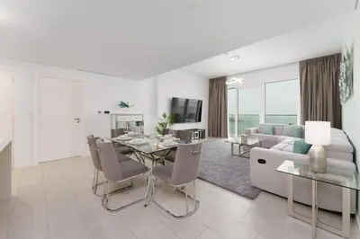 a living room with a dining table and a couch at Maison Privee - Seaside JBR Living w/ Open Sea & Bluewaters Views in Dubai