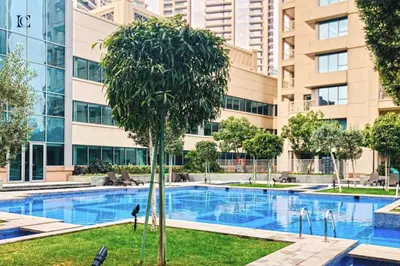 a swimming pool with a tree in front of a building at Luxury Escapes - Modern Studio Apt with Balcony near Dubai Mall - 29 Blvd in Dubai