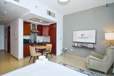 a living room with a table and a kitchen at Luxury Escapes - Modern Studio Apt with Balcony near Dubai Mall - 29 Blvd in Dubai