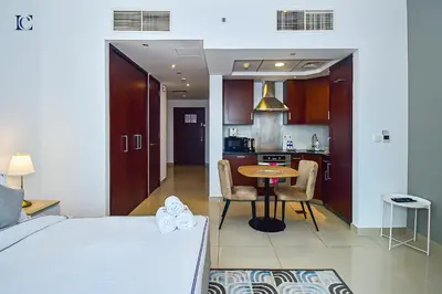 a bedroom with a bed and a table and a kitchen at Luxury Escapes - Modern Studio Apt with Balcony near Dubai Mall - 29 Blvd in Dubai