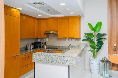 a kitchen with wooden cabinets and a counter top at Escape24 Spacious Studio with Balcony near Dubai Mall in Dubai