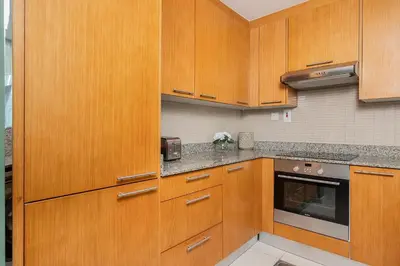 a kitchen with wooden cabinets and a microwave at Escape24 Spacious Studio with Balcony near Dubai Mall in Dubai