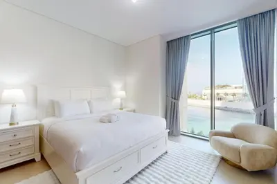 a white bedroom with a bed and a large window at 5242 Tower 2 - Cosy One Bedroom in Dubai