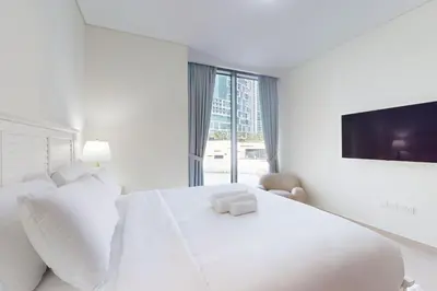 a white bedroom with a large white bed and a tv at 5242 Tower 2 - Cosy One Bedroom in Dubai