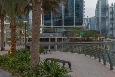 a park with benches and palm trees in a city at Click Stay - JLT - Studio & Balcony Lakes view Entire Apartment -RA in Dubai