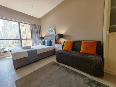 a bedroom with a bed and a couch and a window at Modern, spacious, Luxe 5BR plus Maid condo in JBR, near JBR Beach, Marina view, By La Buena Vida Holiday Homes in Dubai
