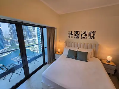 a bedroom with a white bed and a large window at Click Stay - JLT - Entire Studio & Balcony Lakes view Apartment -NA in Dubai