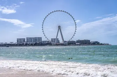 a beach with a ferris wheel in the background at Sea Breeze Oasis in Dubai