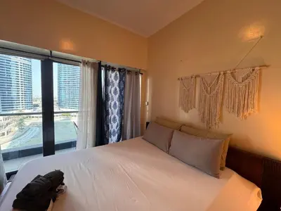 a bedroom with a bed and a large window at Click Stay - JLT - Studio & Balcony Lakes view Entire Apartment -JN in Dubai