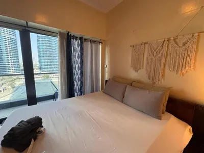 a bedroom with a white bed with a large window at Click Stay - JLT - Studio & Balcony Lakes view Entire Apartment -JN in Dubai