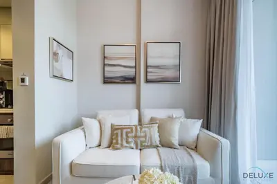 a living room with a white couch and pictures on the wall at Exclusive Rate 1BR with Partial Burj Khalifa Views by Deluxe Holiday Homes in Dubai