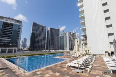 a swimming pool with lounge chairs and umbrellas in a city at Exclusive Rate 1BR with Partial Burj Khalifa Views by Deluxe Holiday Homes in Dubai