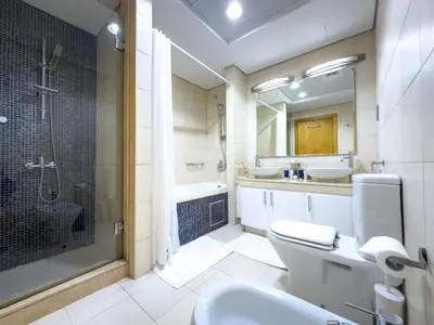 a bathroom with a shower and a toilet and a sink at Bright 2BR Apartment with Garden View - Palm Jumeirah in Dubai