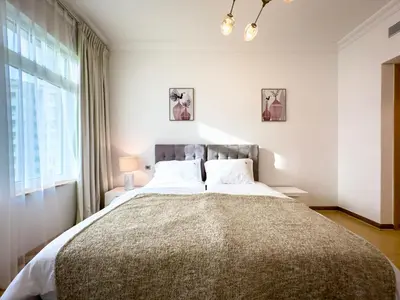 a bedroom with a large bed with a large window at Bright 2BR Apartment with Garden View - Palm Jumeirah in Dubai