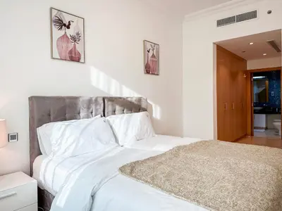 a bedroom with a white bed with a gray headboard at Bright 2BR Apartment with Garden View - Palm Jumeirah in Dubai