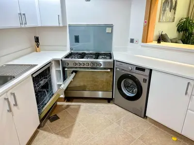 a kitchen with a stove and a washer and dryer at Bright 2BR Apartment with Garden View - Palm Jumeirah in Dubai